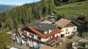 A residential area with houses, a paved road, and a forested hillside.