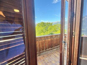 Un balcón de madera con vistas a árboles verdes y montañas.