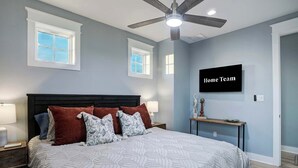 A bedroom with a bed, a ceiling fan, a TV, and a nightstand. - Ultimate Waterfront Escape | Pool, Dock, & Views (Jamaica Beach)