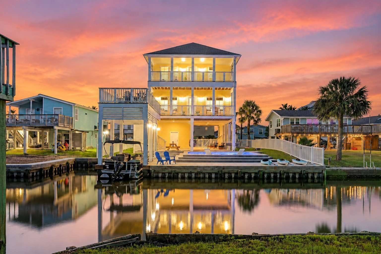 A waterfront property with a two-story house, a dock with boats, and a clear view of the water.