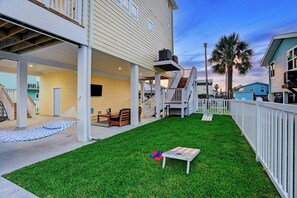 Ein Wohngrundstück mit überdachter Terrasse, einer Hängematte, Gartenmöbeln und einer kleinen Spielzone.