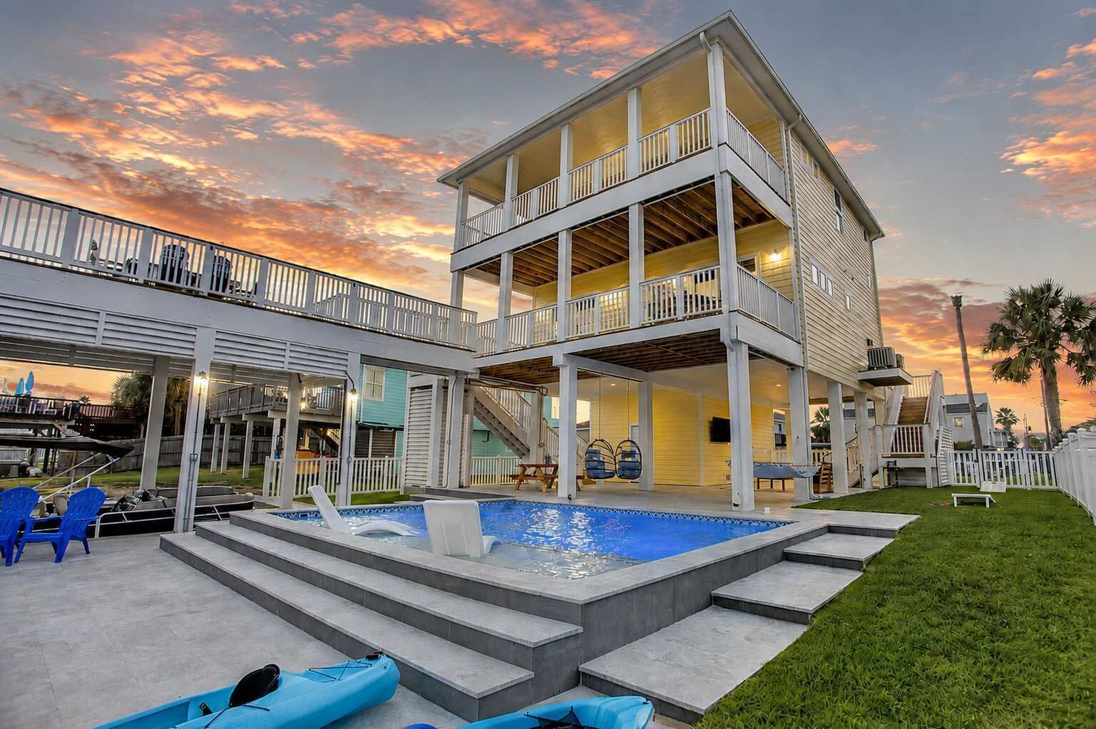 A two-story house with a pool, outdoor seating, and a covered patio area.