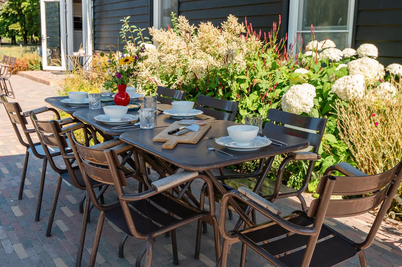 Un espace extérieur aménagé pour les repas, avec une table dressée pour quatre personnes, entourée de chaises.