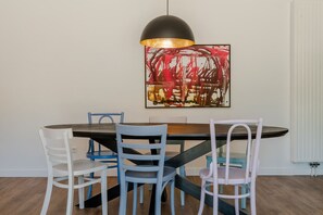 A dining area with a round table, four chairs, a pendant light, and a large abstract painting on the wall. - Holiday home with 5 bedrooms in Ossenisse | Het Hoogland B (Ossenisse)