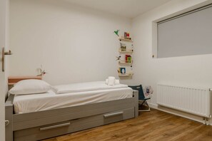 Ein Schlafzimmer mit einem Einzelbett, einem Nachttisch, einem Heizkörper und einem Regal mit Büchern und Dekoration.