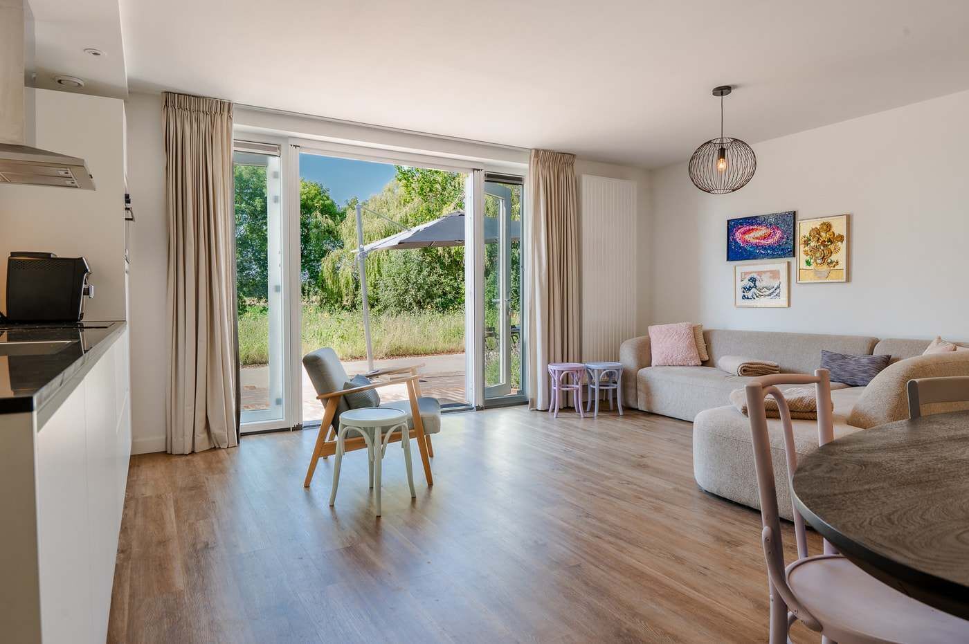 Una sala de estar moderna con sofá, sillas, una mesa de comedor y una zona de cocina con televisor.