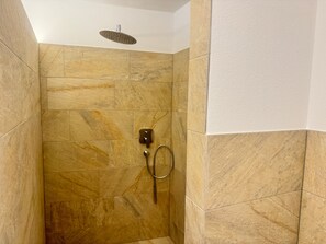 Un área de ducha con cabezal de ducha manual y controles empotrados en la pared.