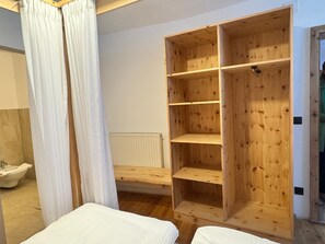 Una habitación con un armario de madera, una cama y un baño con un radiador blanco.