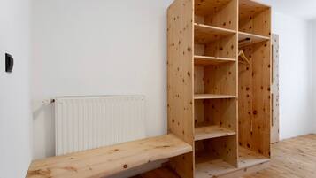 A room with a wooden wardrobe, a white radiator, and a wooden bench.