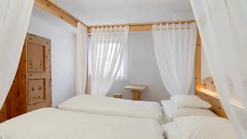 Une chambre à coucher avec une tête de lit en bois, un arbre à chat et des rideaux en voile.