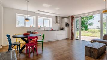 A modern kitchen with a dining area, large windows, and a view of the outdoors.