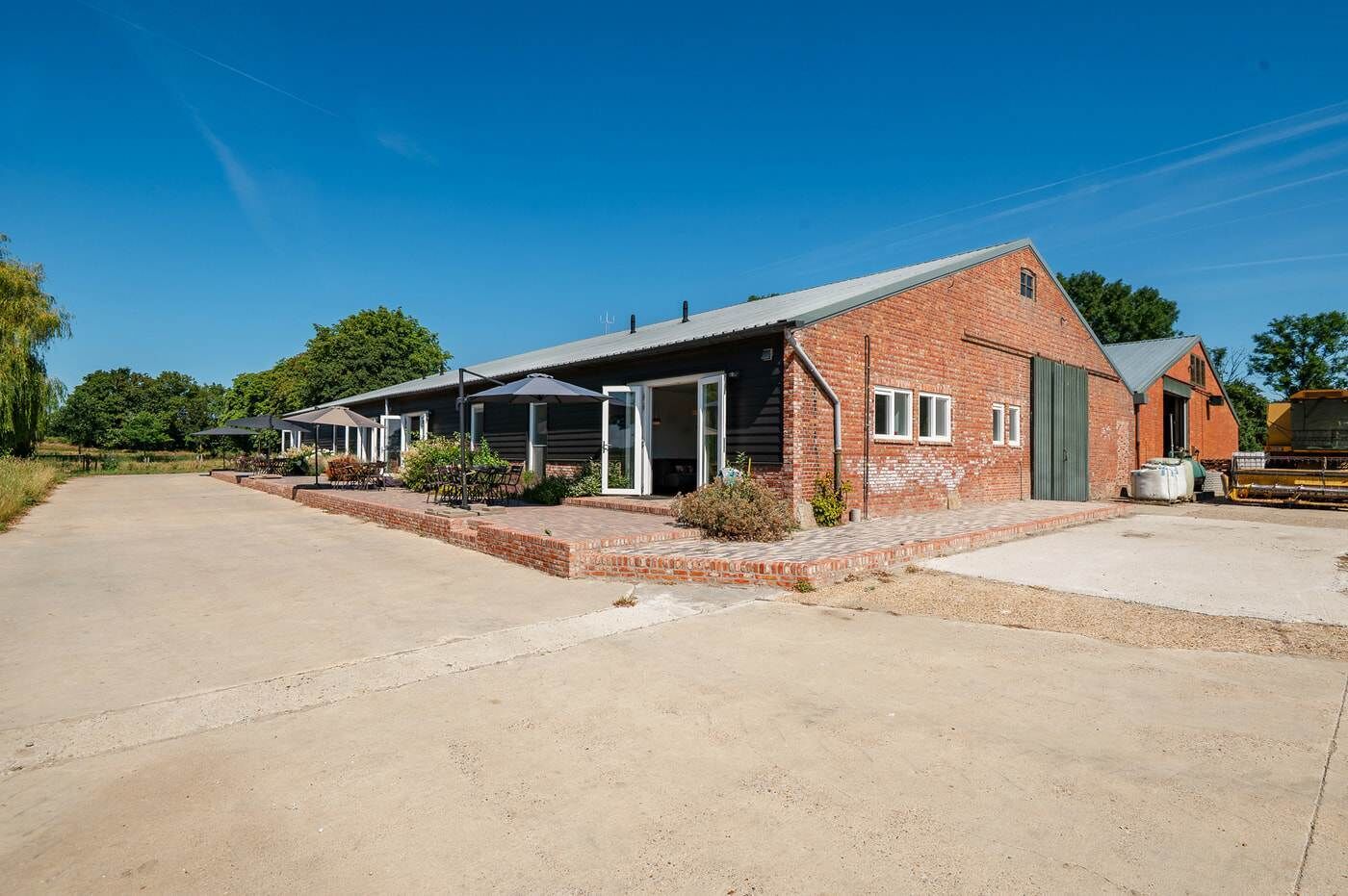 A brick building with a covered patio area, a garage, and a small adjacent structure.