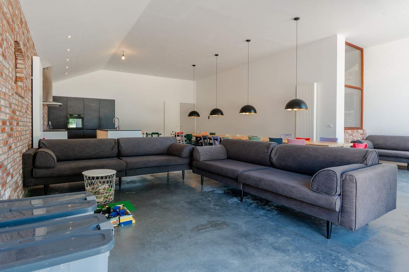 A modern living room with a sectional sofa, a coffee table, and a kitchen in the background.
