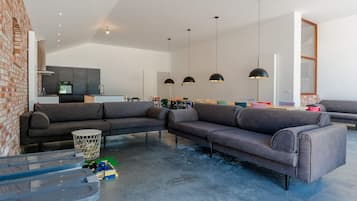 A modern living room with a sectional sofa, a coffee table, and a kitchen in the background.