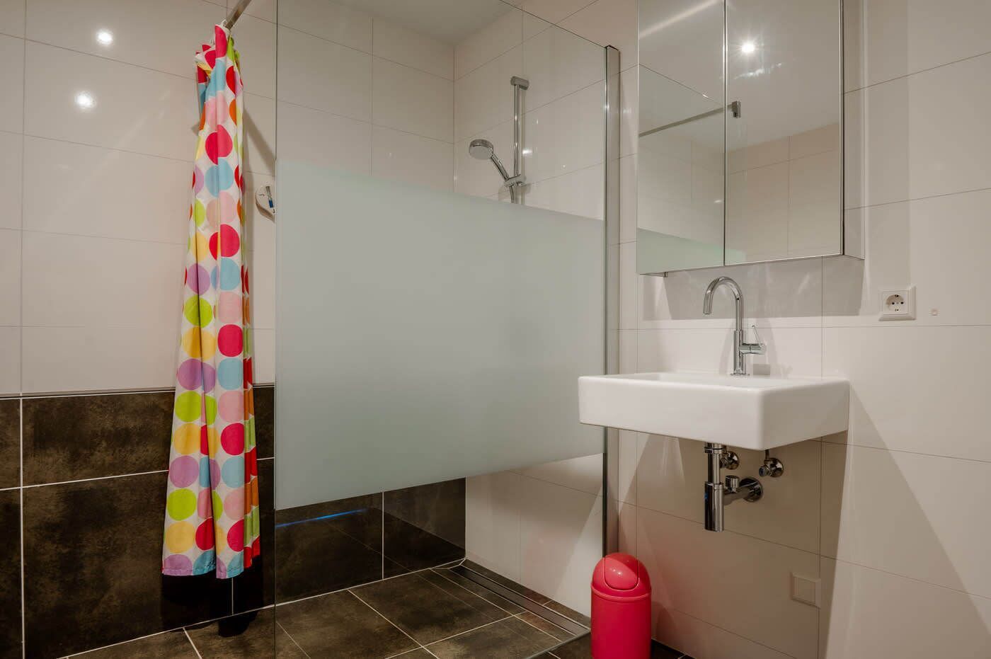 A bathroom with a shower, a sink, and a mirror.