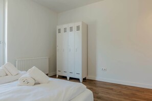 A bedroom with a bed, white towels, a radiator, and a white wardrobe. - Holiday home in Ossenisse | Het Hoogland C (Ossenisse)