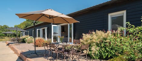An outdoor patio with a brick border, outdoor furniture, and umbrellas.