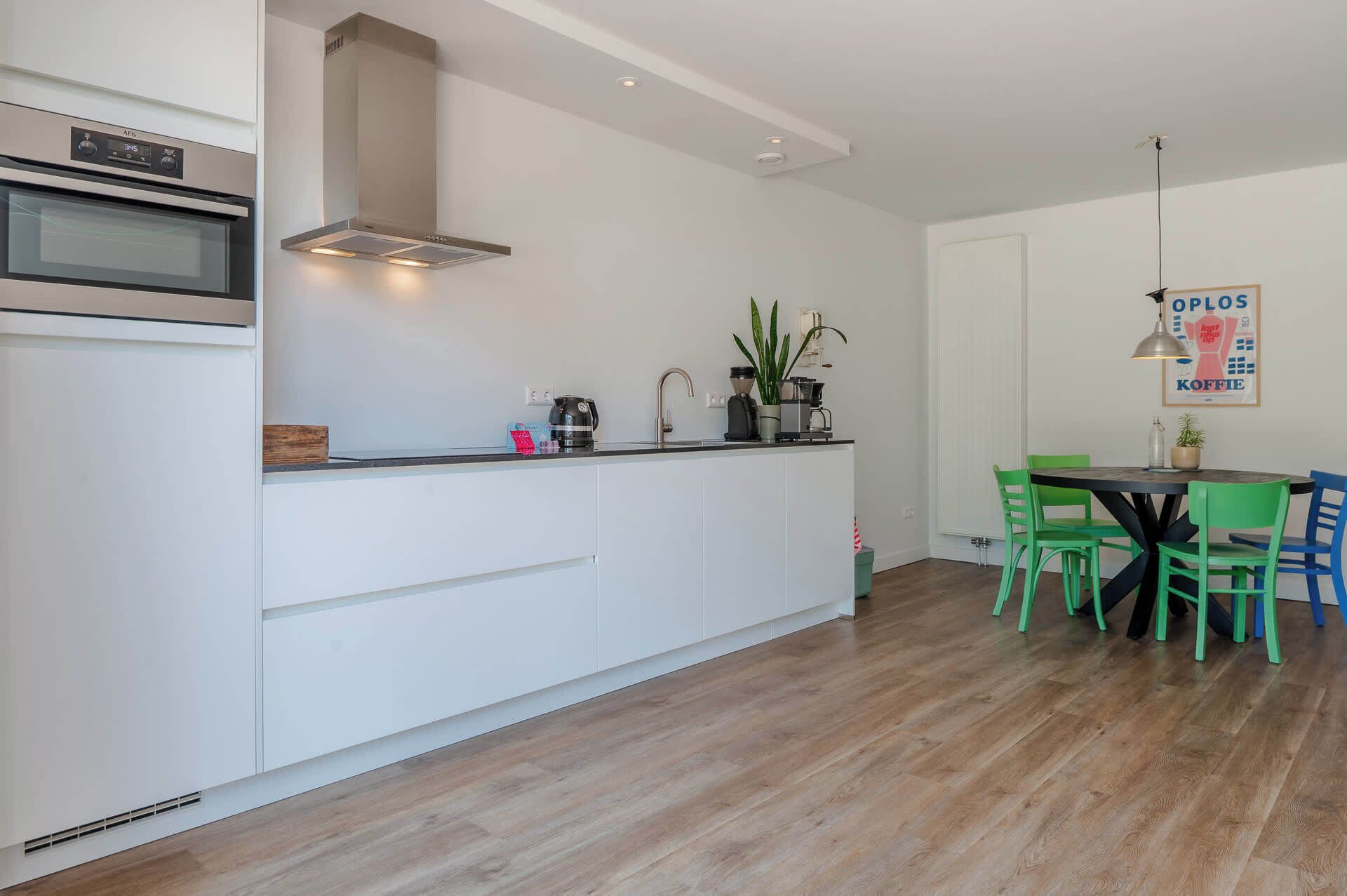 Eine moderne Küche mit Einbauofen, Dunstabzugshaube und Essbereich mit Tisch und Stühlen.