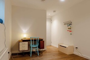 A room with a wooden desk, a chair, a lamp, a pegboard with push pins, and a small storage unit. - Holiday home in Ossenisse | Het Hoogland C (Ossenisse)