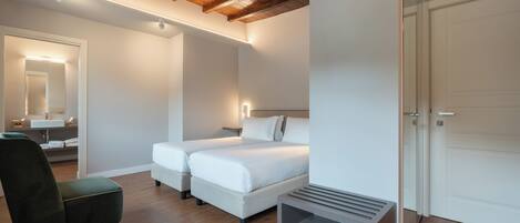 Une chambre avec deux lits, une table de chevet, une chaise, un miroir et une armoire.