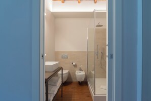 Uma casa de banho moderna com chuveiro, sanita e lavatório.
