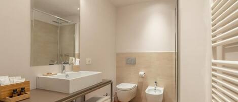 A modern bathroom with a large mirror, a sink, a toilet, and a bidet.