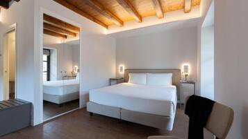 Une chambre à coucher avec un lit, des tables de chevet, une chaise et un miroir.