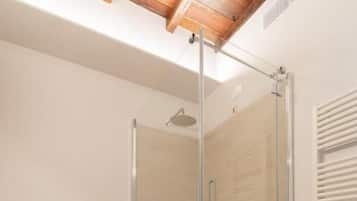 Une salle de bain dotée d’une douche à parois de verre, d’un bidet et d’un plancher en bois.