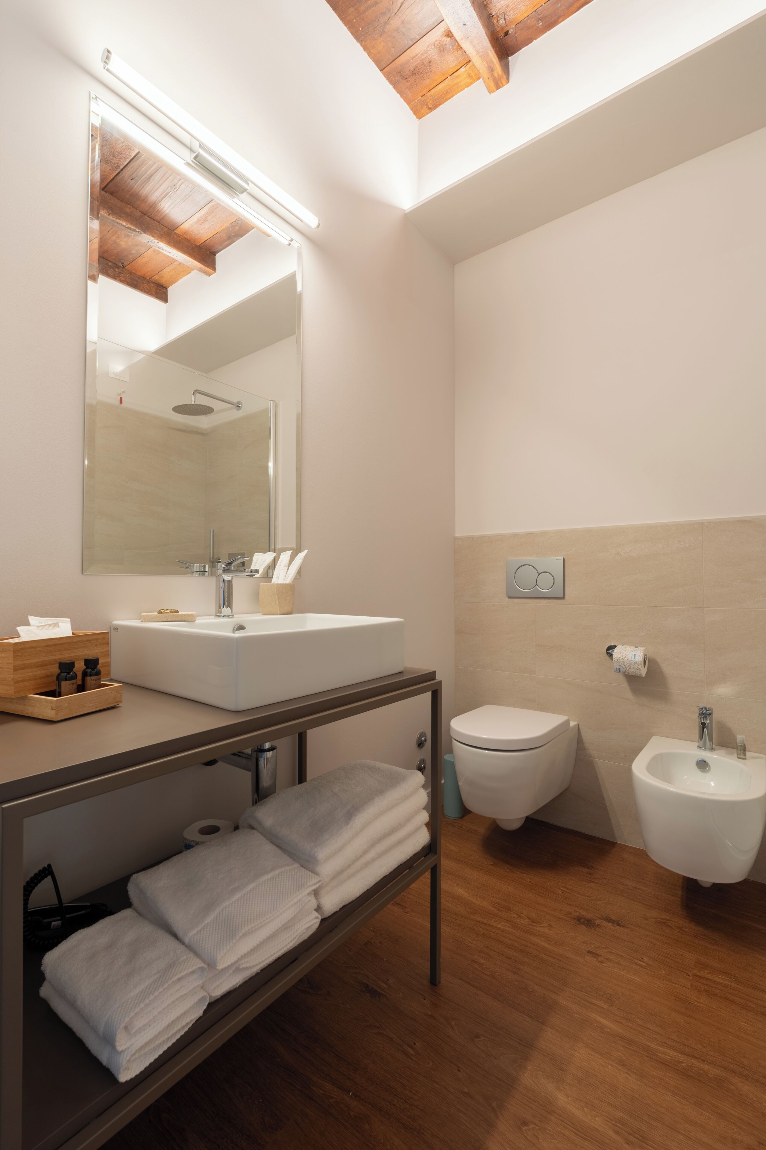 Un baño moderno con un espejo grande, un lavamanos, un bidé y un perchero para toallas.