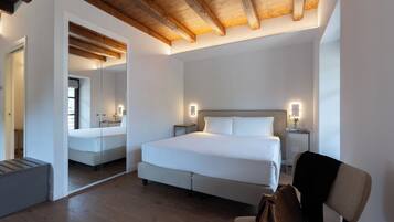 Un dormitorio moderno con una cama grande, mesitas de noche, un espejo y techo de madera.