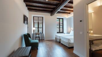 A compact hotel room with a bed, a desk, a chair, and a small table.