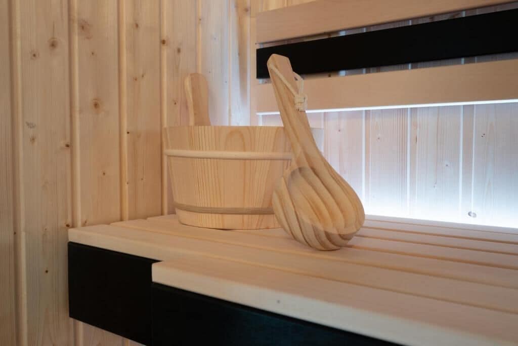 A wooden sauna bench with a wooden ladle and a wooden bucket.