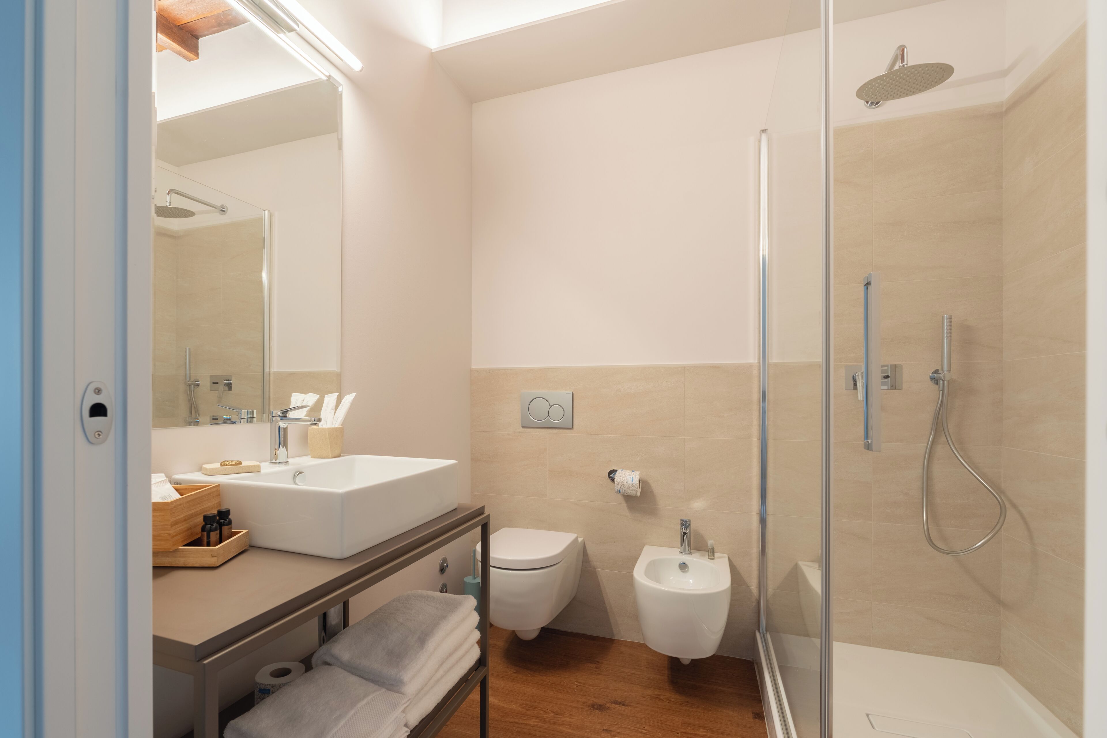 Ein modernes Badezimmer mit einer Glaskabine zur Dusche, einem Waschbecken, einer Toilette und einem Bidet.