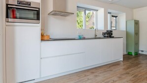 Una cocina moderna con horno empotrado, extractor, ventana y radiador.