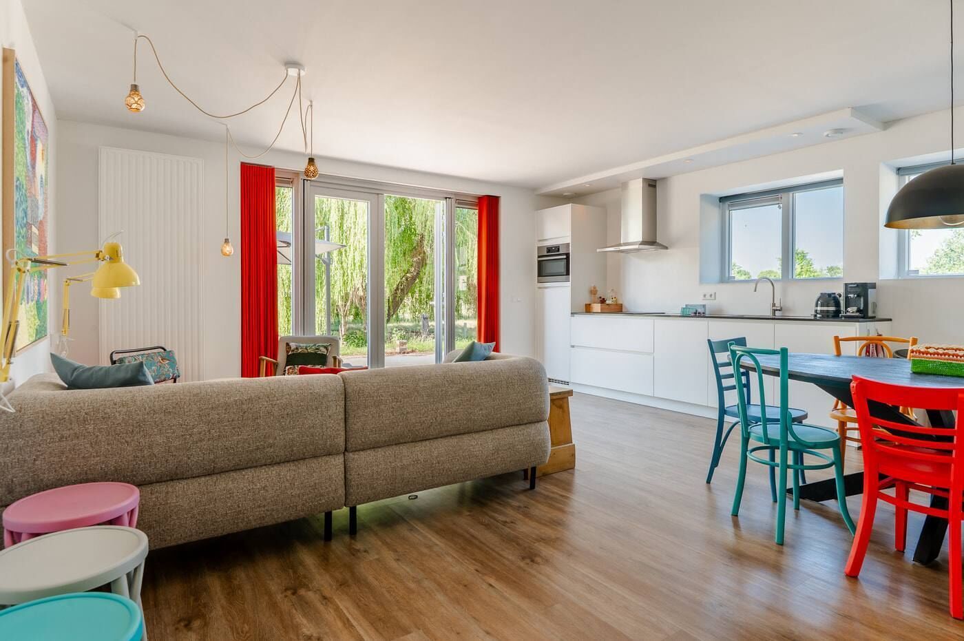 A modern living room with a sofa, a dining table with chairs, and a kitchen area with a stove and cabinets.