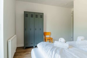 Ett hotellrum med två sängar, en trästol och en uppsättning grå skåp.