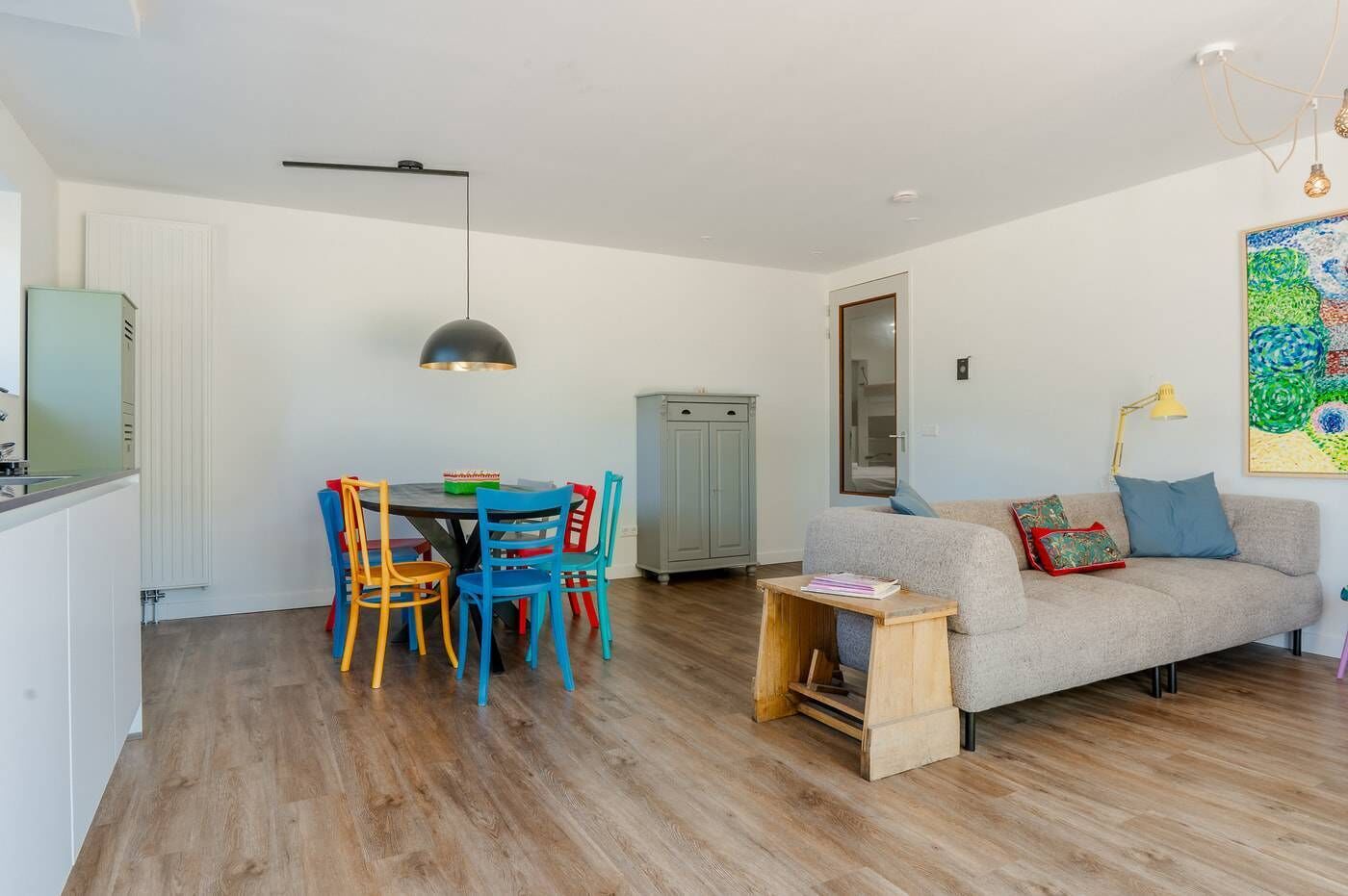 A compact living space with a dining area, a sofa, and a wooden side table.