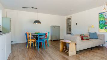 A compact living space with a dining area, a sofa, and a wooden side table.