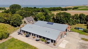 Un edificio industrial grande con techo plano, paneles solares y entrada pavimentada.