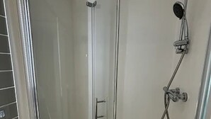 A glass-enclosed shower stall with a handheld showerhead and a wall-mounted faucet. - Student Only Bridle Works (Glasgow)