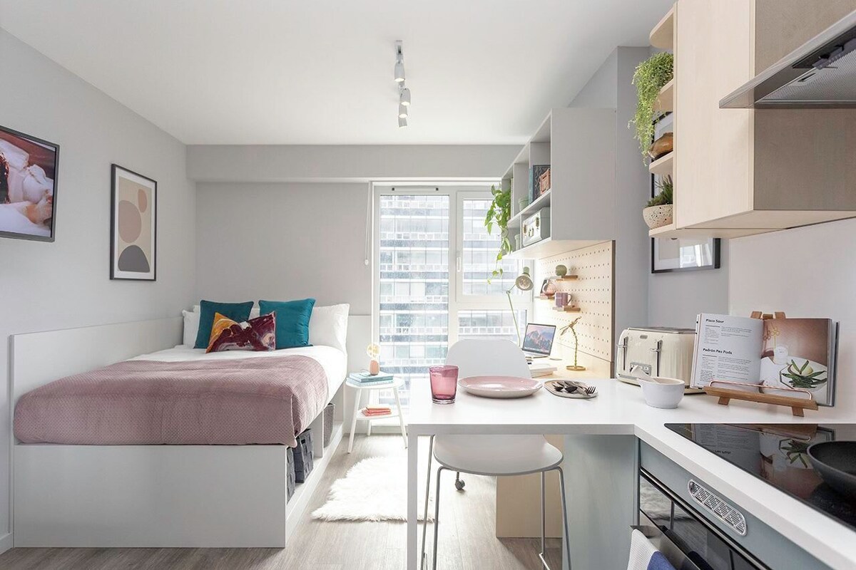 A modern, compact living space with a bed, a dining area, and a kitchenette.