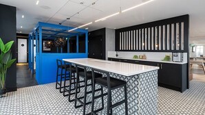 A modern kitchen with a central island, bar stools, and a patterned floor. - Student Only Bridle Works (Glasgow)