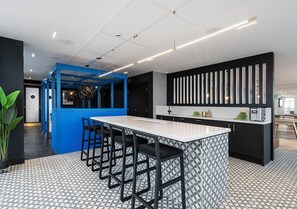 A modern kitchen with a central island, bar stools, and a patterned floor. - Student Only Bridle Works (Glasgow)