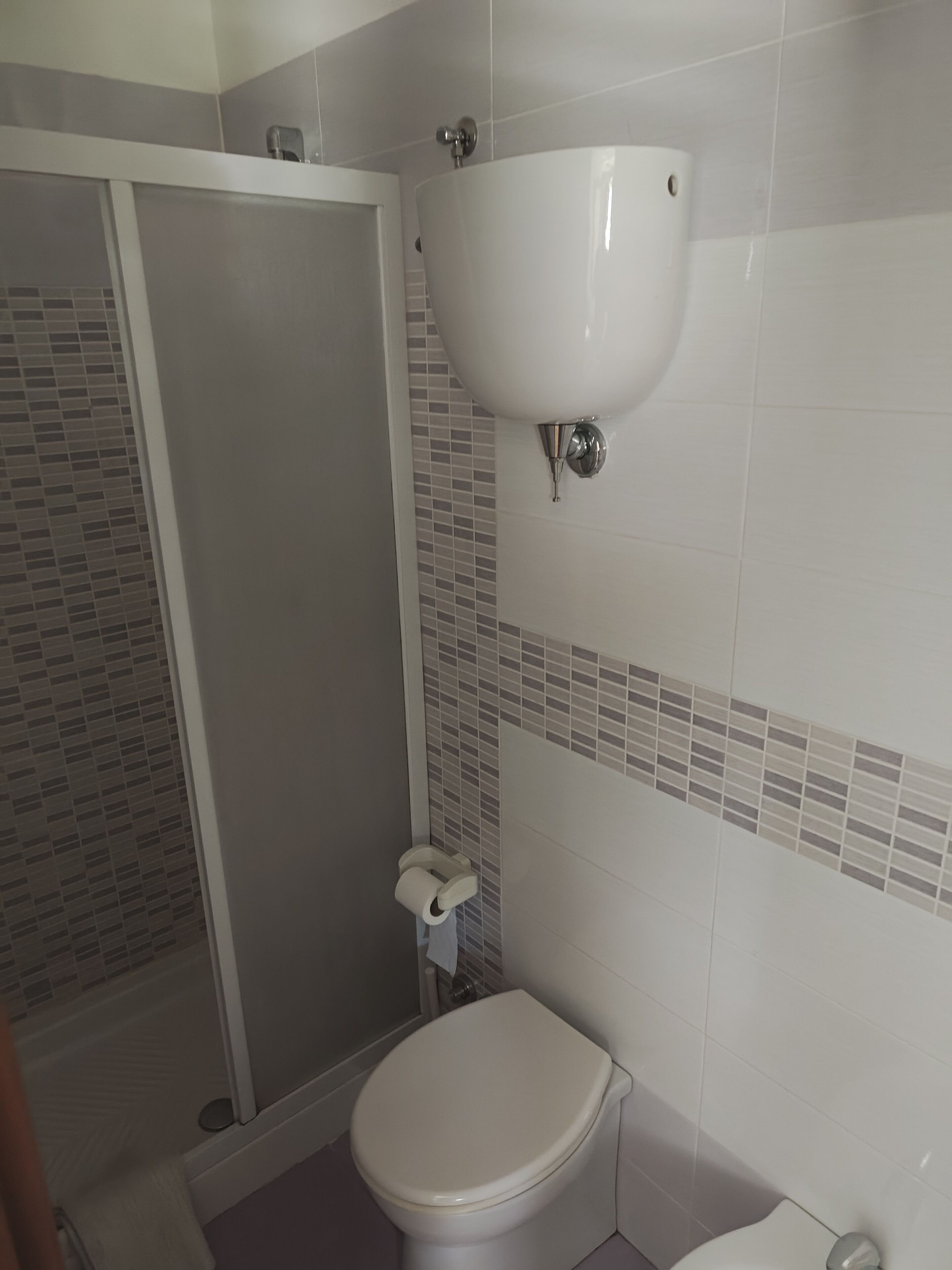 Kylpyhuone, jossa on wc, pesuallas ja suihkukaappi.