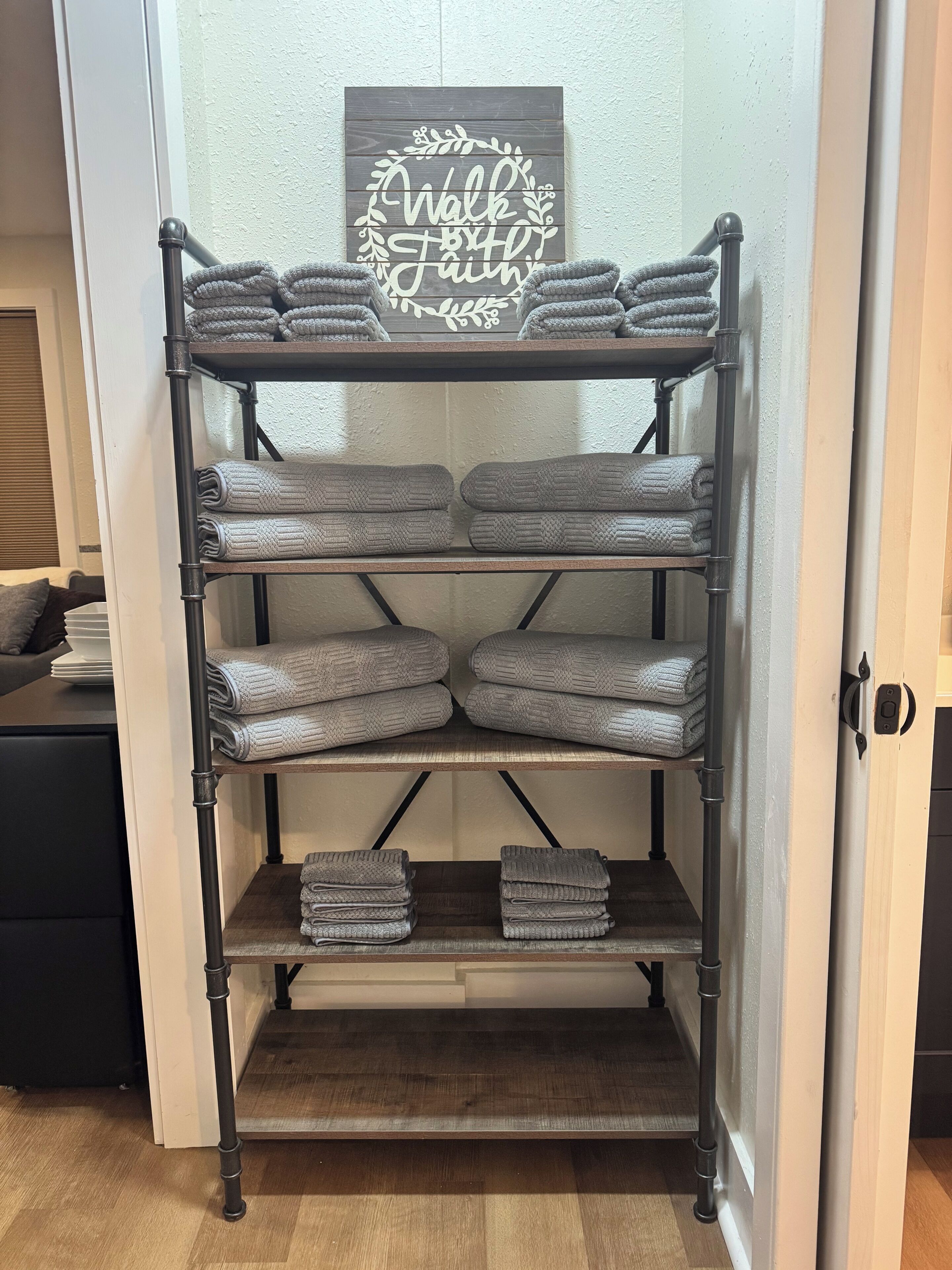 A metal shelving unit with folded towels and a decorative sign above it.