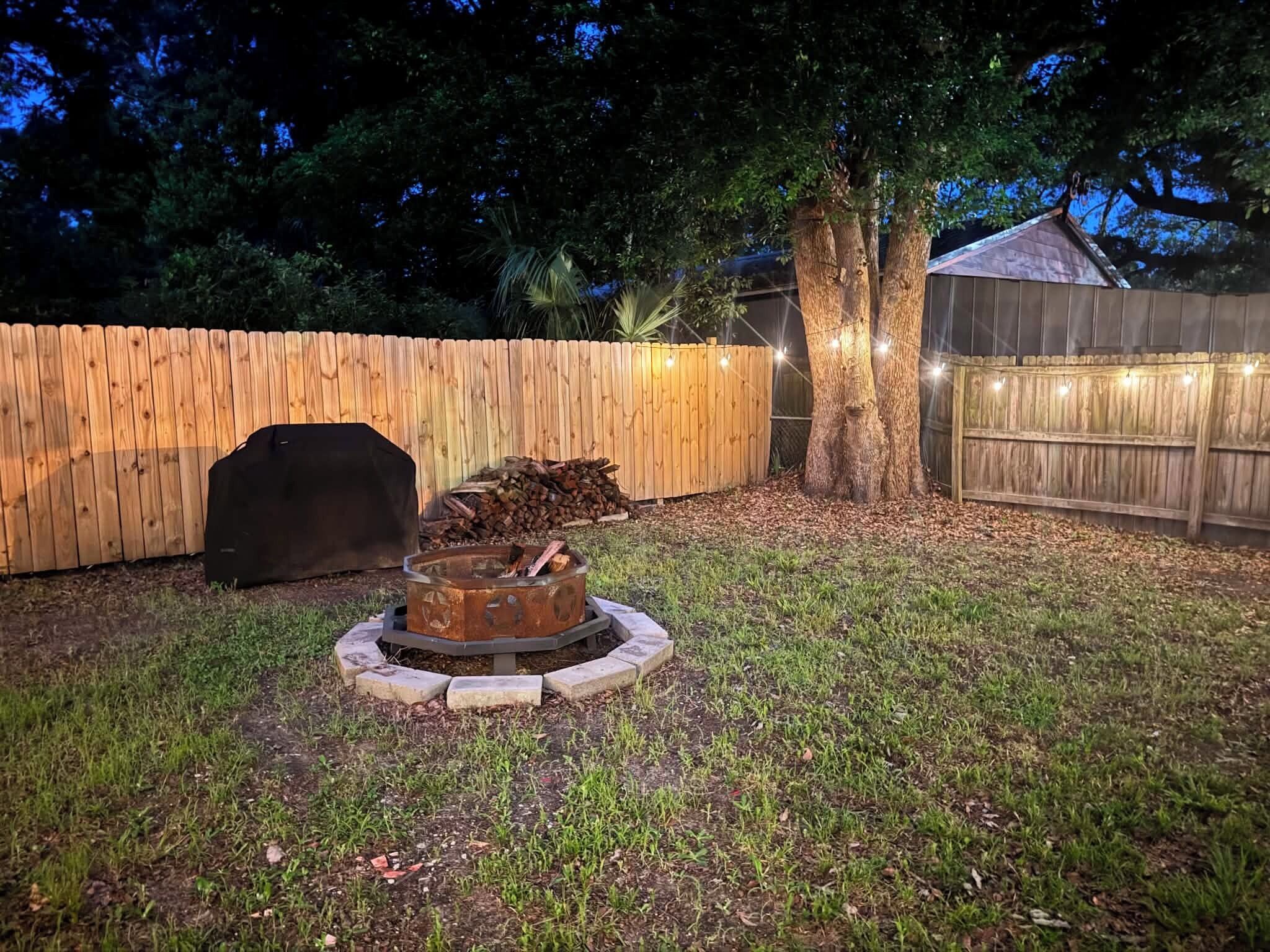 Un cortile con un braciere, un barbecue e un recinto in legno.