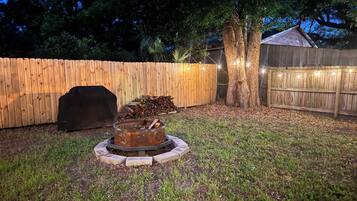 Un cortile con un braciere, un barbecue e un recinto in legno.