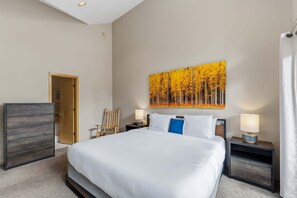 Ein Hotelzimmer mit einem großen Bett, einer Holzkommode, einem Sessel, zwei Nachttischen mit Lampen und einem Bild an der Wand.