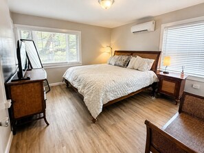 A bedroom with a bed, a desk, a chair, a lamp, and a window with blinds. - Cozy 2-bedroom house in beautiful Bay St. Louis with AC (Bay St. Louis)