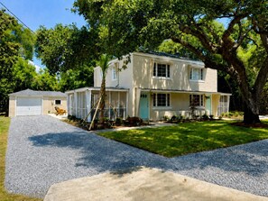 A two-story house with a garage, a front porch, and a tree in the yard. - Cozy 2-bedroom house in beautiful Bay St. Louis with AC (Bay St. Louis)